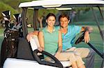 Couple Riding In Golf Buggy On Golf Course