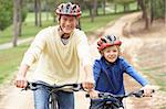 Grandfather and grandson riding bicycle in park