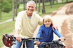 Grandfather and grandson riding bicycle in park