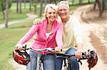 Senior couple riding bicycle in park