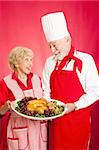 Chef und Hausfrau arbeitete er an einem köstlichen Urlaub Türkei Abendessen machen. Roter Hintergrund.