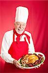 Chef holding a Thanksgiving or Christmas turkey stuffed on a platter.