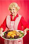 Pretty grandmother serving holiday turkey dinner.  Red background.