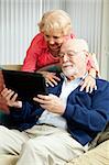 Senior couple de détente à la maison, à l'aide de leur tablet PC.