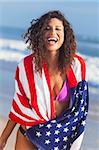 Belle jeune femme riant port bikini et serviette drapeau américain sur une plage ensoleillée