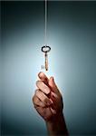 Conceptual image of a hand taking an old key hanging from a string.