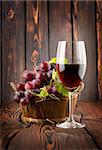 Wine glass and grapes in a basket on a wooden background