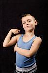 Un jeune garçon exhibant ses muscles sur fond noir