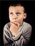 Boy with hand on chin and looking up trying to solve a problem