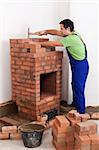 Worker building a brick stove arranging the building blocks of the firebox