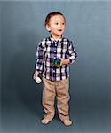 Cute baby standing in studio with toys in his hands