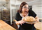 Woman with Excited Facial Expression Holding Apple Pie in Bakery Kitchen