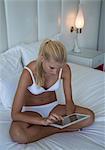 Frau mit Tablet PC auf dem Bett