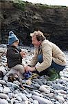 Father and son playing on rocky beach