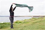 Woman playing with scarf in grassy field