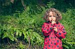 Girl holding finger over lips in forest