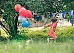 Girl holding bunch of balloons outdoors