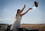 Newlywed bride tossing bouquet from car