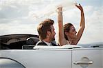 Newlywed couple riding in convertible