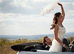 Newlywed couple riding in convertible