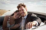 Newlywed couple riding in convertible