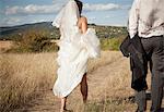 Newlywed bride holding up dress in grass