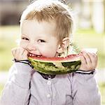 Toddler girl eating watermelon outdoors