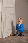 Junge sitzt auf Holzboden