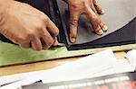 Close up of hands cutting leather