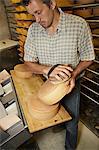 Worker finishing wheel of cheese in shop