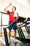 Man drinking water on treadmill at gym