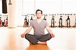 Man meditating on mat at gym