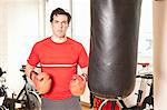 Homme à l'aide de sac de boxe au gymnase