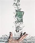 Main tenant le billet d'un dollar dans l'eau