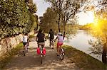 Family riding bicycles by river bank