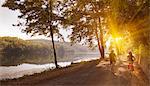 Couple riding bicycles by river bank