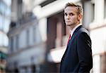 Portrait of handsome businessman in suit standing against building