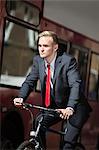 Young businessman riding bicycle by bus