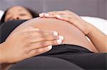 Young pregnant woman relaxing with hands on stomach