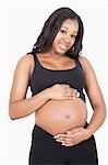 Portrait of happy young pregnant woman with hands on stomach over white background