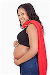 Portrait of happy young pregnant woman wearing superhero cape over white background