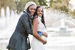 Portrait of happy young woman embracing pregnant woman from behind