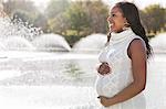 Happy young pregnant woman looking away in park