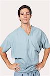 Portrait of confident man in surgical scrubs standing against gray background