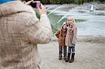 Mother taking photo of children in front of fountain