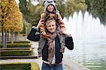 Portrait of father carrying son on his shoulders at park