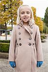 Portrait of cute little girl in winter coat standing at park