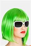 Young woman wearing green wig over gray background