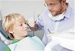 Boy looking Anxiously at Dentist holding a Needle during Appointment, Germany