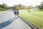 Two Boys Wearing Knapsacks and Walking through Neighbourhood on Way to School